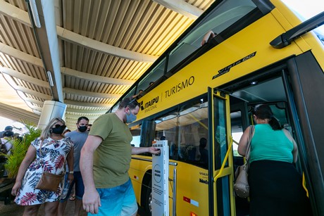 Turistas embarcam no ônibus de turismo fazendo uso de álcool em gel, no Centro de Recepção de Visitantes da Margem Esquerda da Itaipu Binacional.  